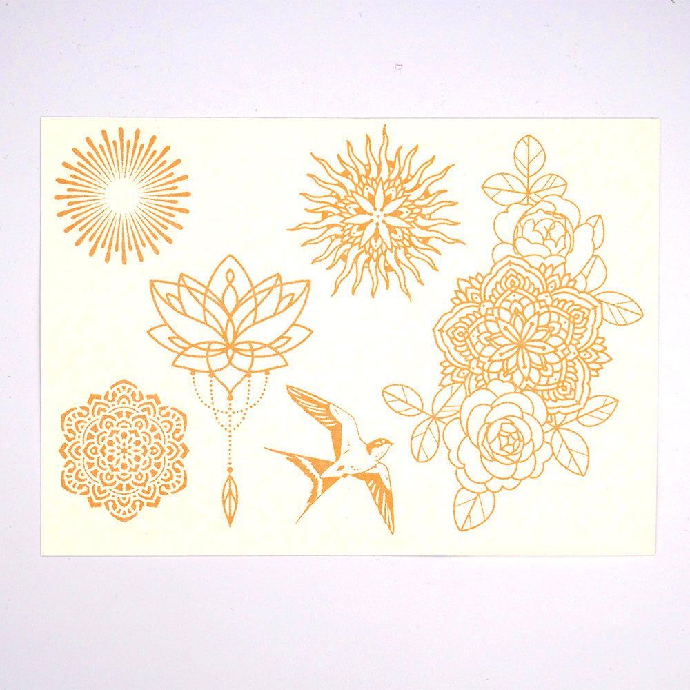 Das Organic Tattoo-Set von TrendRaider zeigt kunstvolle Blumen- und Sonnendesigns mit einem Vogel in Gold auf weißem Hintergrund und verströmt eine an Mandalas erinnernde Boho-Atmosphäre.