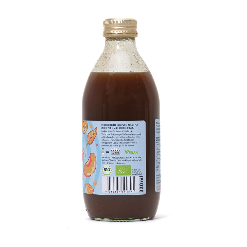 Eine Flasche brauner Sodabär Sirup Pfirsich Eistee von Sodabär mit hellblauem Etikett mit Cartoon-Früchten, BIO-Zutaten und goldenem Verschluss.