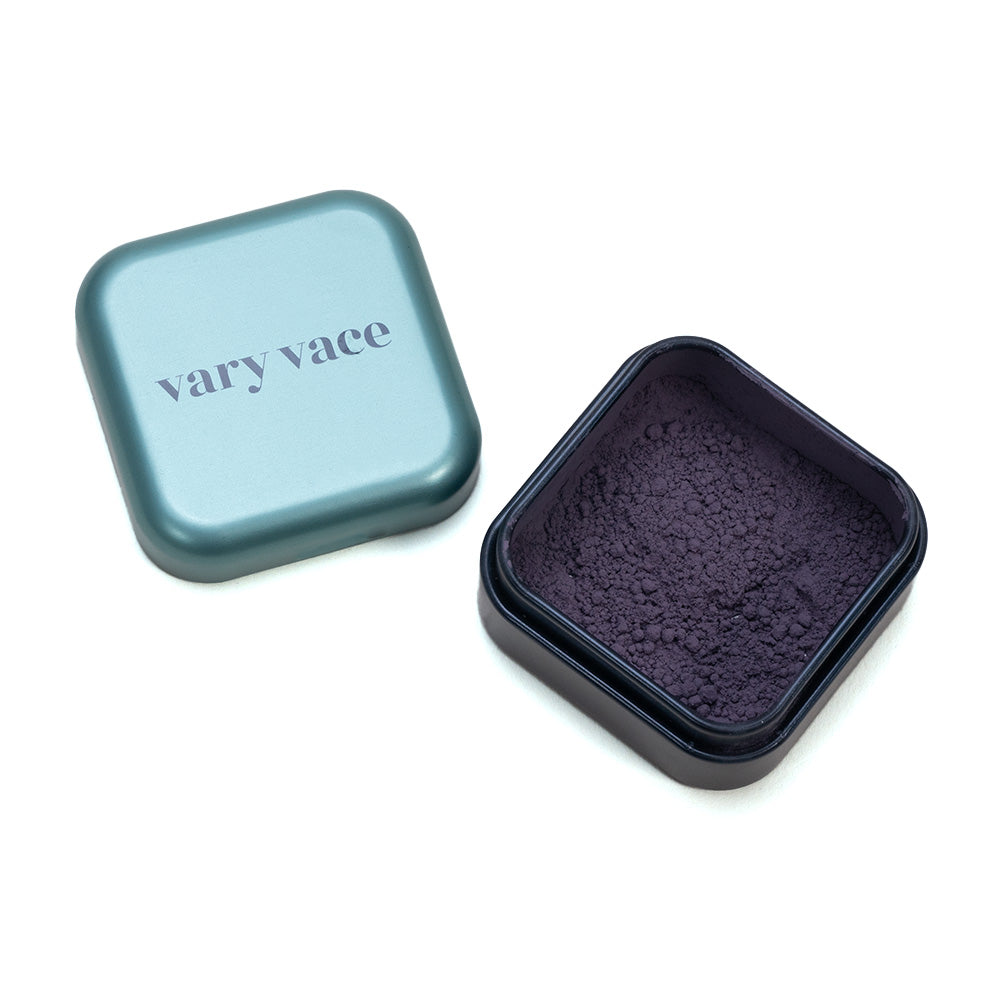Öffnen Sie den quadratischen blaugrünen „Vary Vace“-Behälter und entdecken Sie das violette Puder von Eye Shadow Julie, ideal für Smokey Eyes.