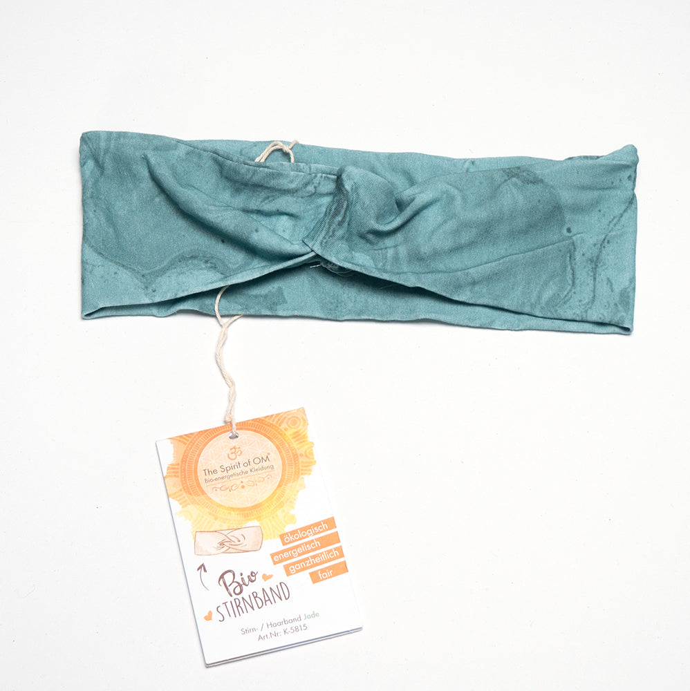 Ein blaugrünes geknotetes Stirnband mit der Aufschrift „Bio Stirnband – Spirit of OM“ von Spirit of OM hängt elegant herab und verkörpert mühelose Mode. Mit Sorgfalt und Stil gefertigt, bietet es sowohl Flair als auch Nachhaltigkeit, da es stolz biozertifiziert ist.