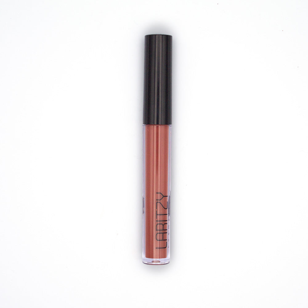 Eine Tube von Laritzys Liquid Lipstick in Pastellbraun mit schwarzer Kappe steht anmutig auf weißem Hintergrund. Freuen Sie sich über die langanhaltende Deckkraft, die den ganzen Tag hält.
