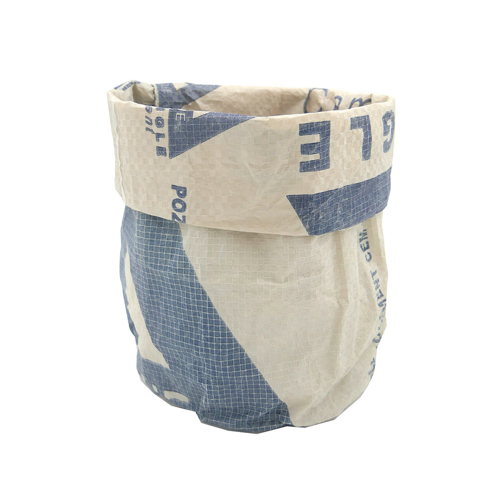 Das Utensilo von NYUZI BLACKWHITE ist eine zylindrische Tasche, nachhaltig hergestellt, aus einem recycelten Zementsack mit blauen und weißen Designs.