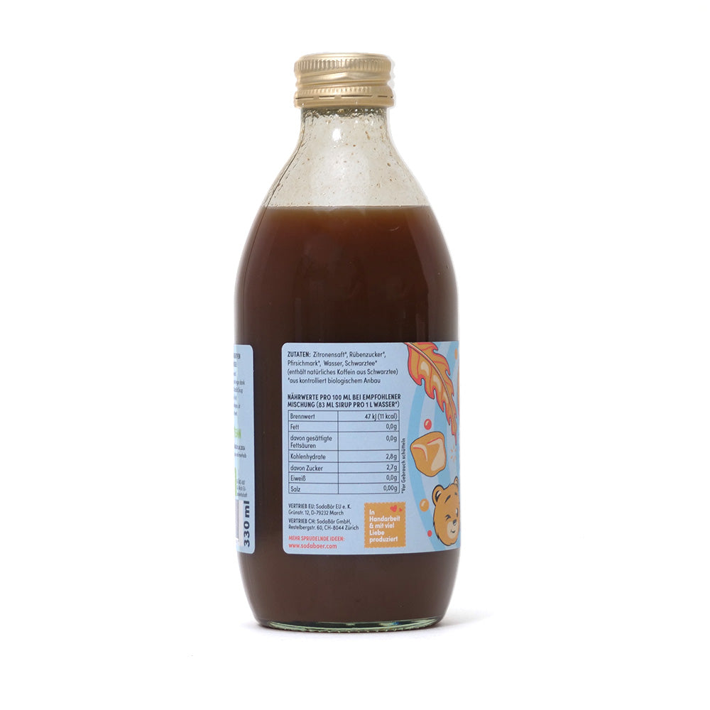 Eine Flasche Sodabär Sirup Pfirsich Eistee mit hellbraunem Deckel und Cartoon-Grafiken auf dem Etikett, die neben Nährwertinformationen auch die veganfreundlichen Zutaten präsentieren.